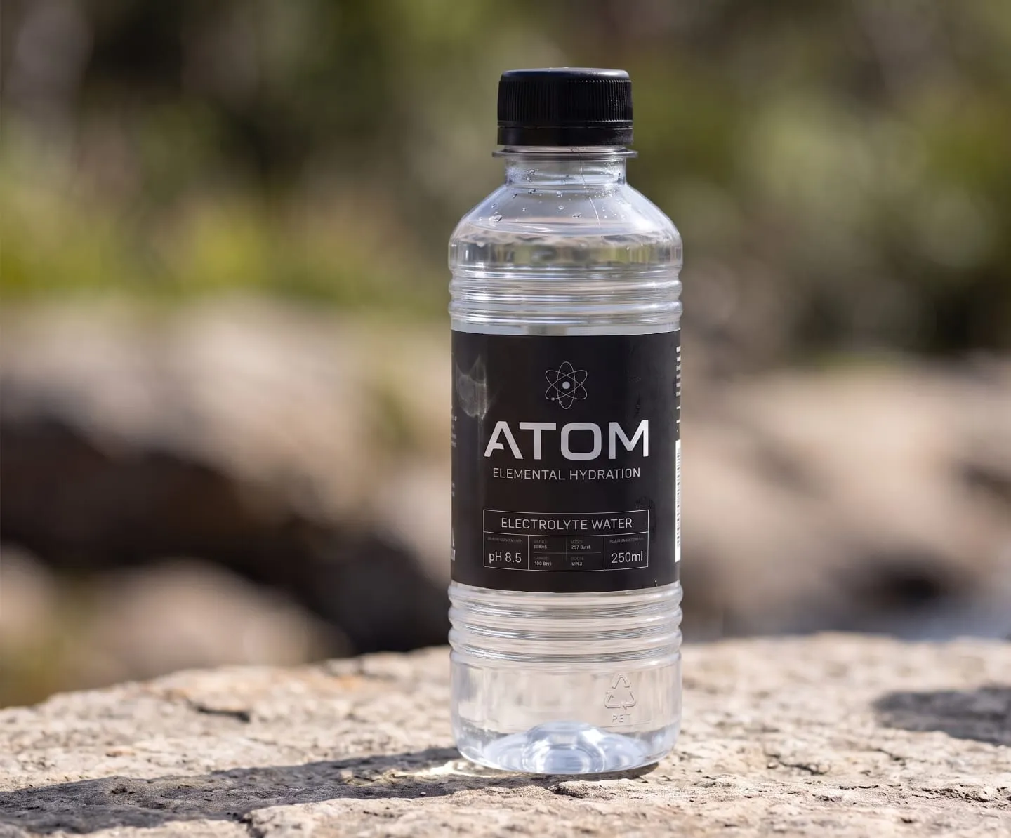 ATOM 250 ml bottle standing on a sunlit rock